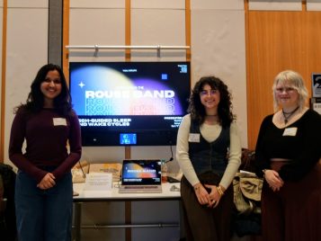 Kerri “K” Graham, Rachel Oliver, and Aanya Mishra standing in front of their project, "ROUSE Band: Guiding the Sleep Cycle with Wearable Tech."